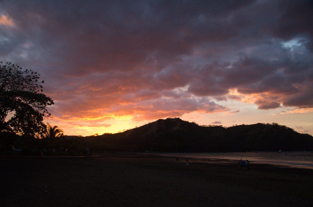 Storm clouds glowing at sunset over the beach and hills of Playas del Coco