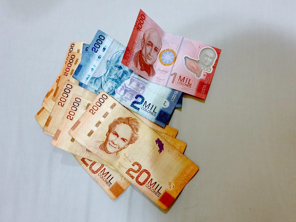 Costa Rican colones banknotes of several denominations spread on a white sheet