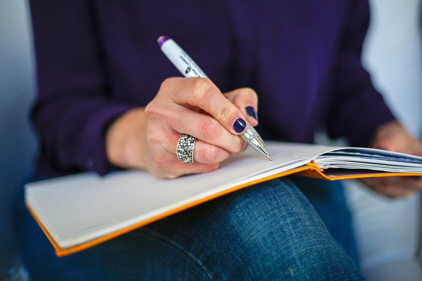 Woman writing a moving abroad checklist in a notebook with a pen