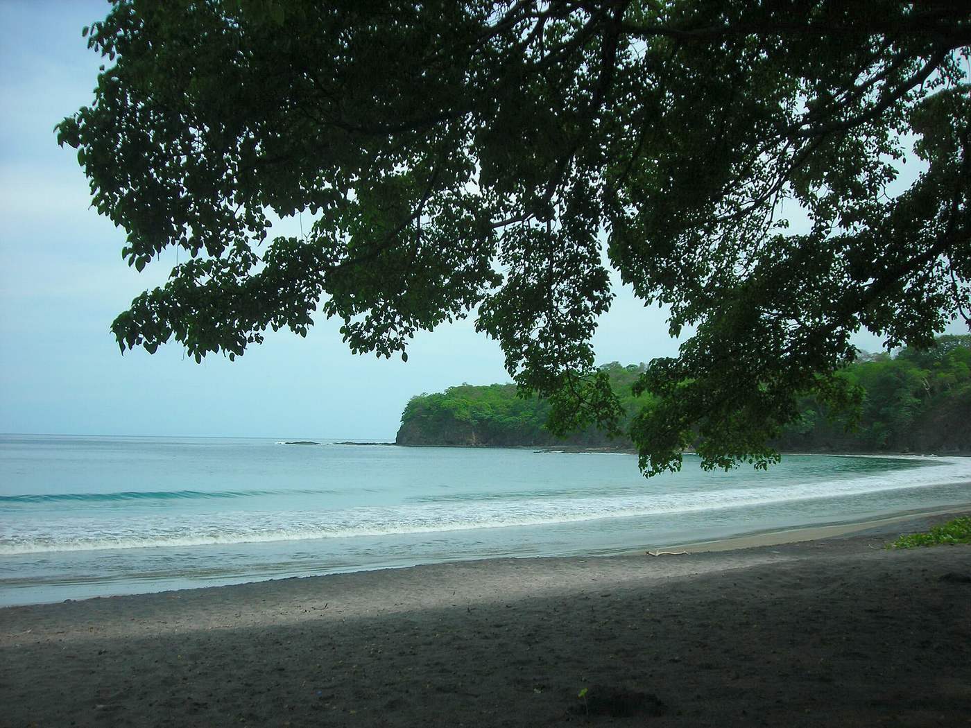 Calm dark sand cove with forested headland on Costa Rica's Papagayo Gulf