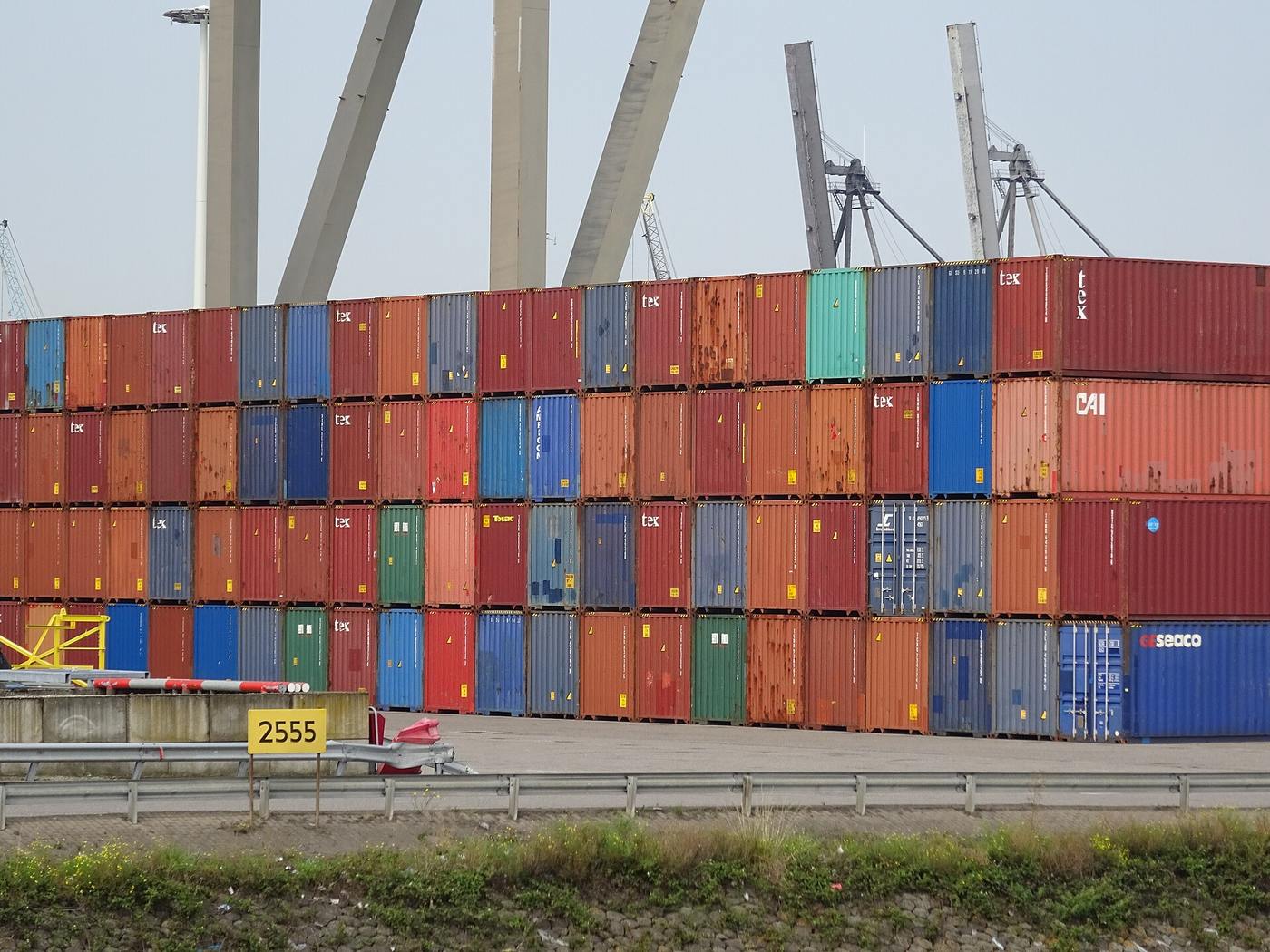 Colorful stacked shipping containers and port cranes at an international cargo terminal