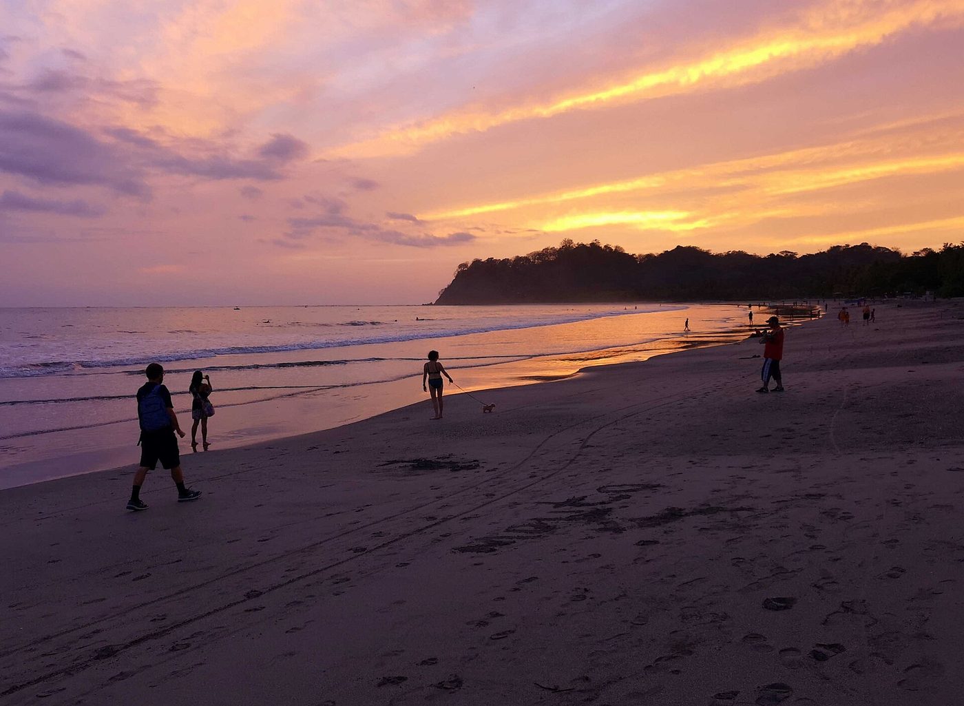 Residents stroll a Guanacaste beach at sunset with a dog in tow