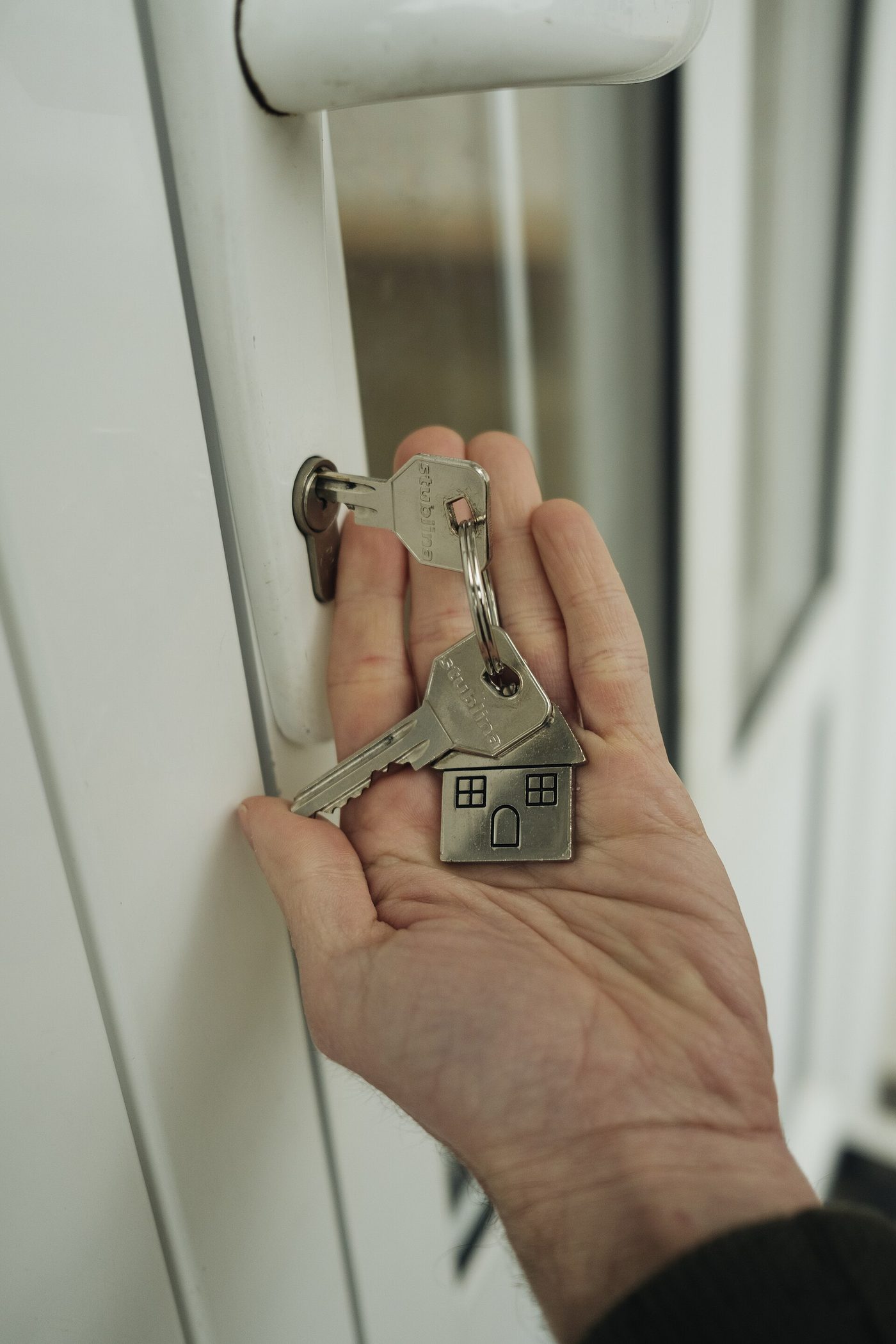 Hand holding house keys at a front door lock before a guest arrives