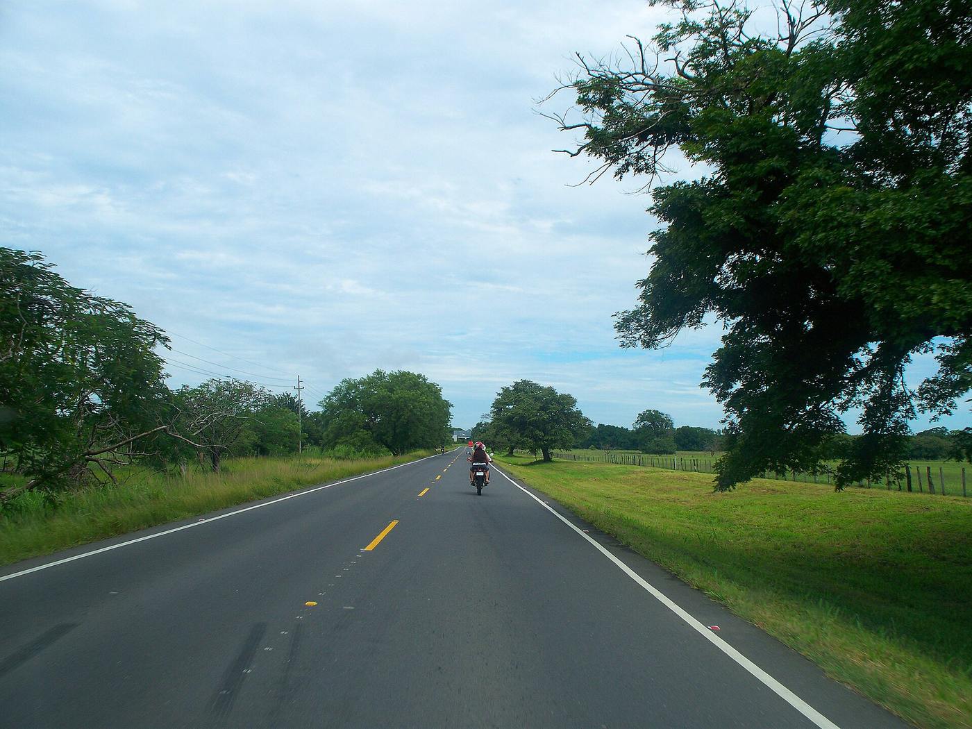 Driver's view of the Pan-American Highway crossing green Guanacaste pastureland
