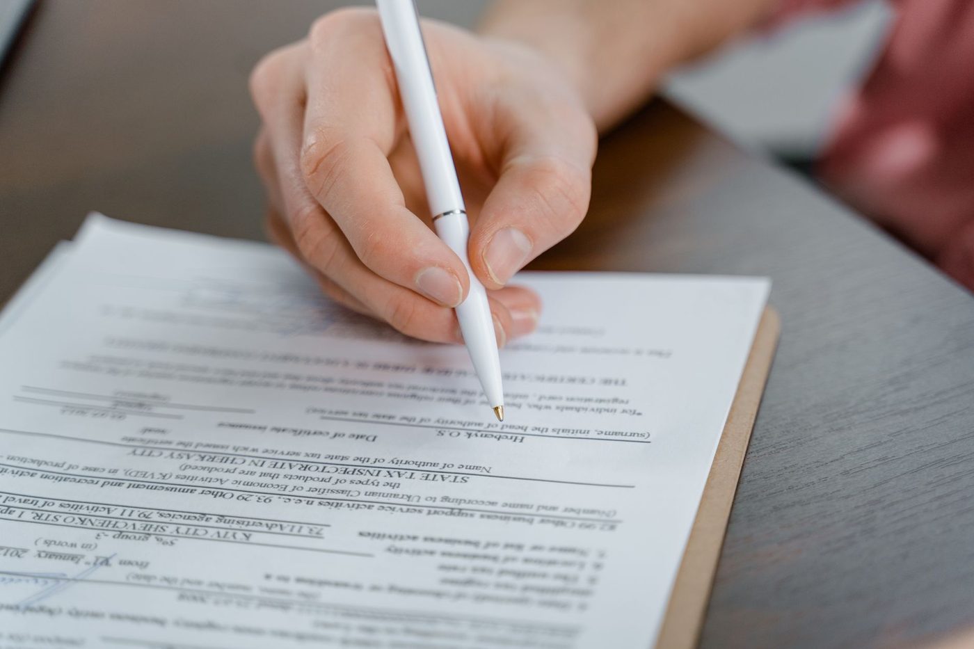 Close-up of a hand signing a printed document with a white pen