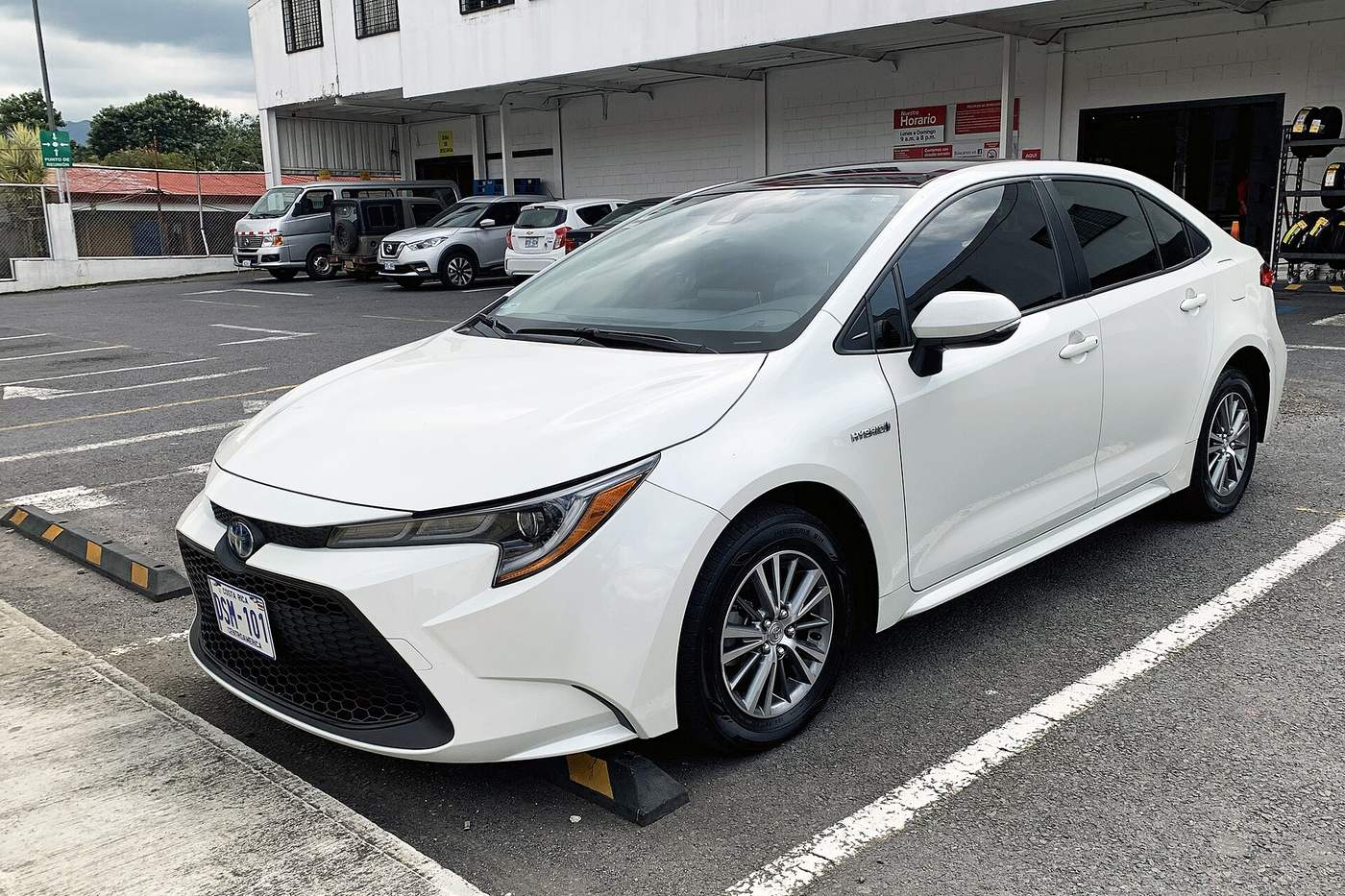 White Toyota Corolla hybrid with Costa Rican plates parked outside a local business