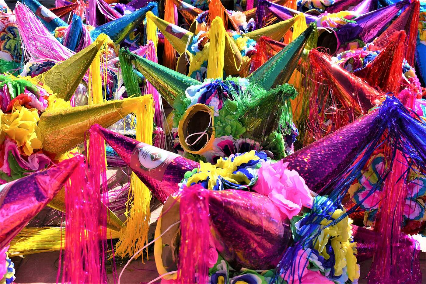 Dozens of brightly colored star pinatas with shiny cones and paper flowers