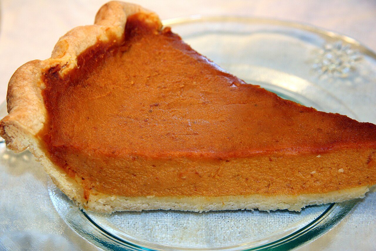 Slice of homemade pumpkin pie served on a clear glass plate