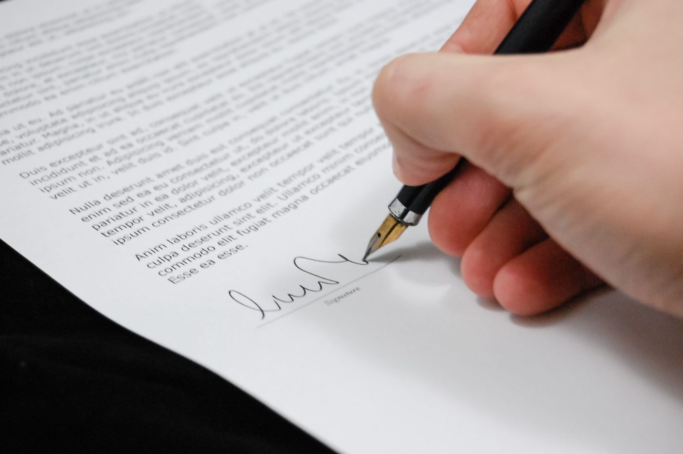 Close-up of a hand signing a legal document with a fountain pen at closing