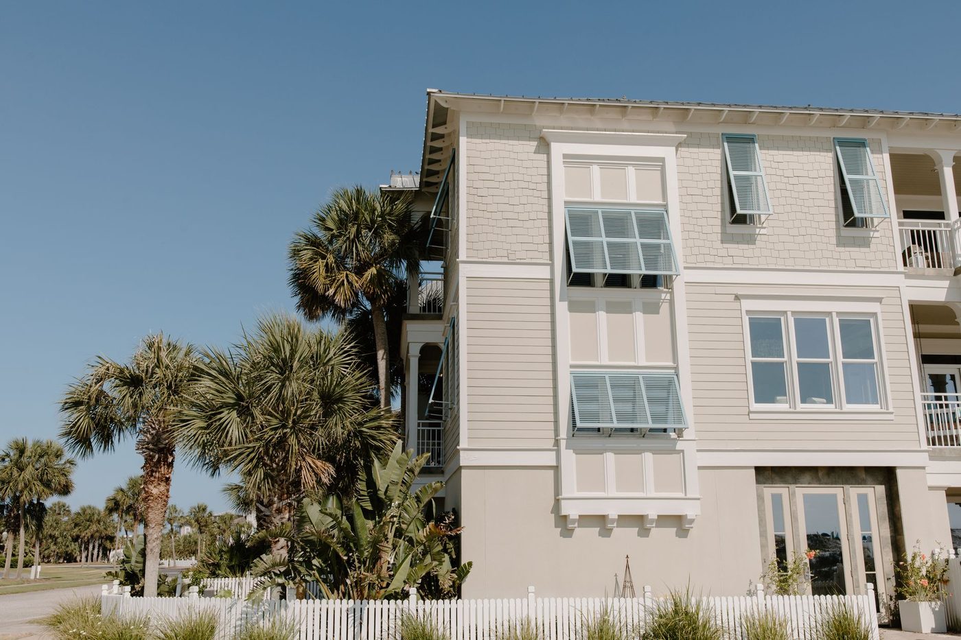 Standalone beach house exterior with shuttered windows and tropical palm landscaping