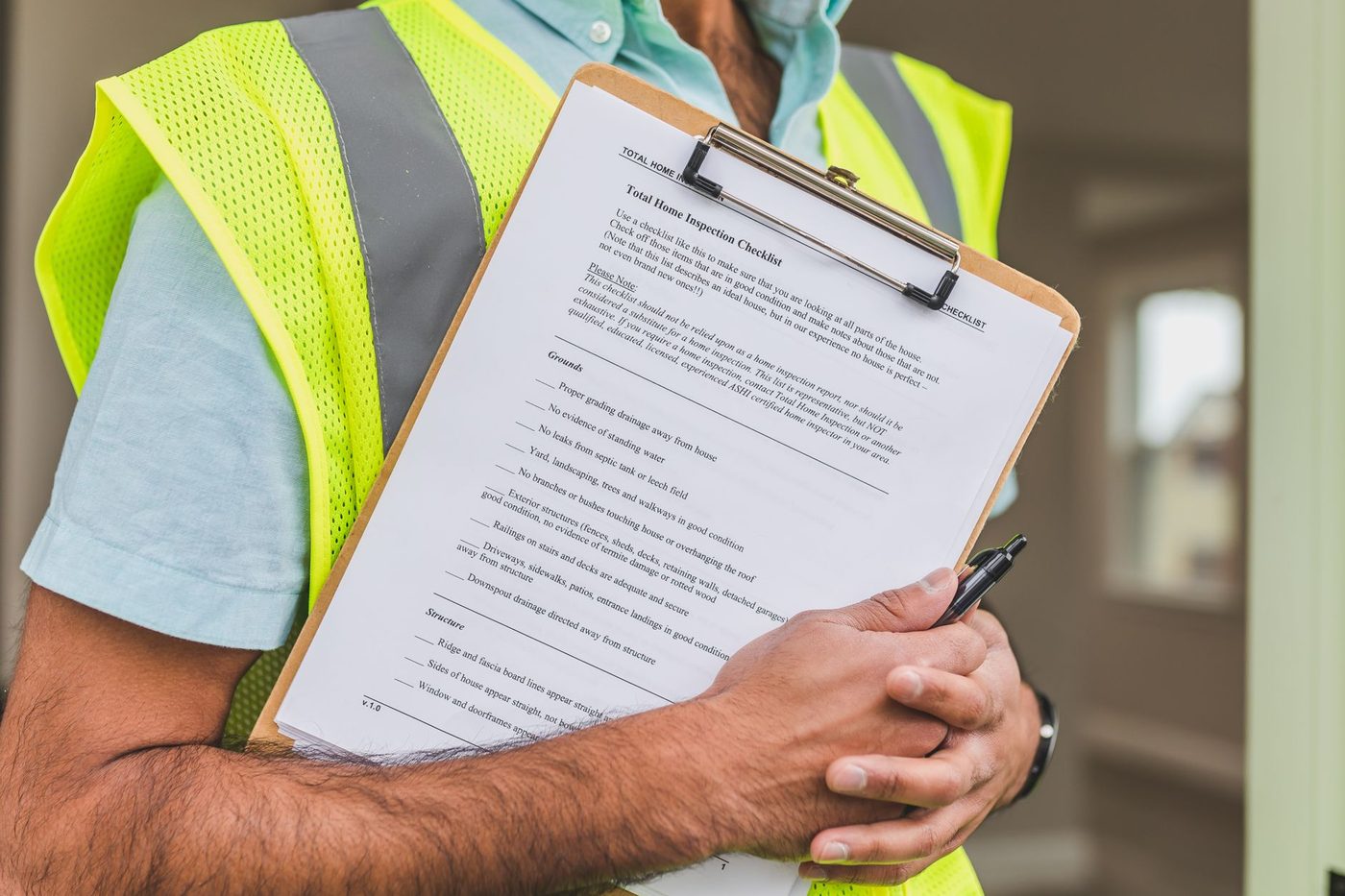 Close-up of a hand holding a pen and a written home inspection checklist
