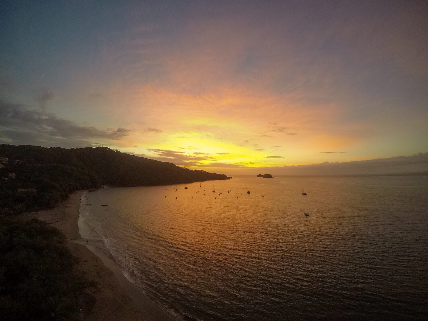 Sunset over Playa Hermosa bay in Guanacaste with boats anchored offshore