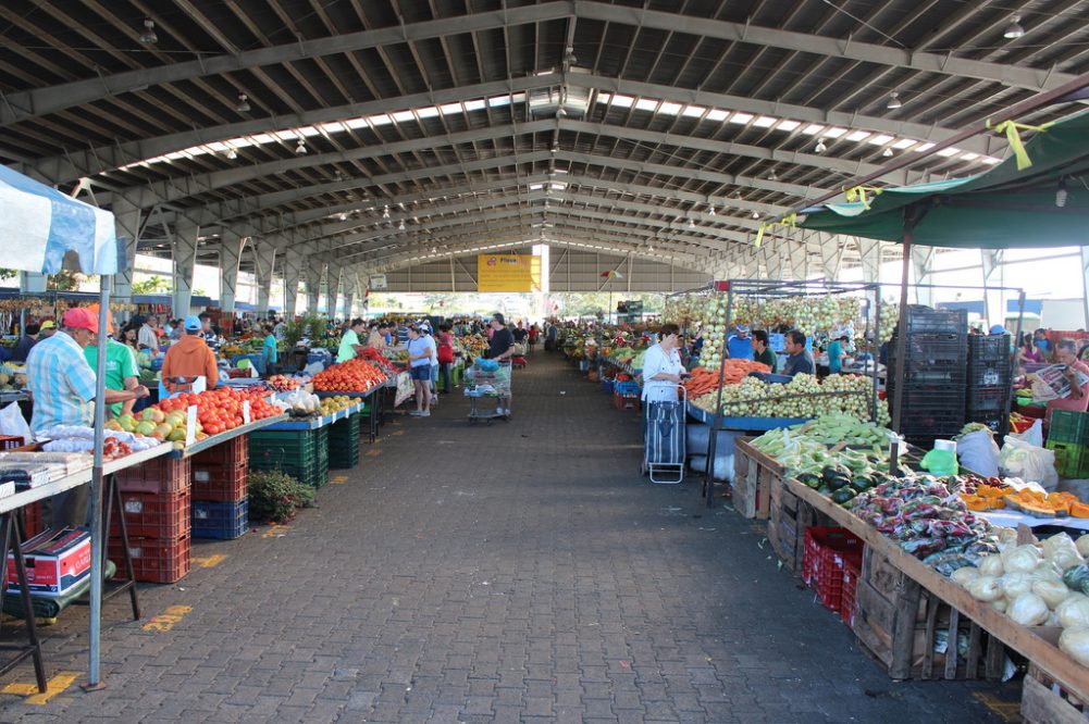 Shoppers browsing produce stalls under the roof of a Costa Rican feria del agricultor