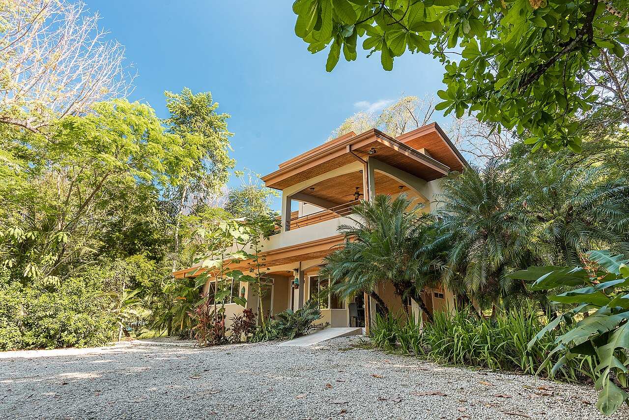 Two-story tropical villa with wooden balconies framed by palms in Costa Rica