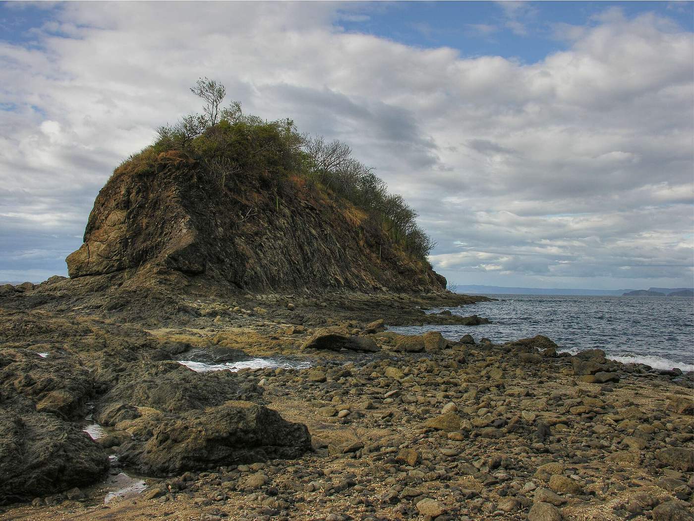 Rocky point with cactus and shrubs at the quiet edge of Playas del Coco's bay