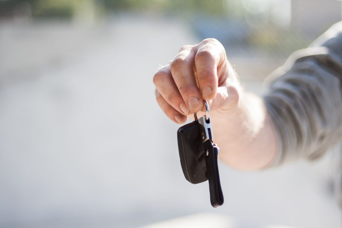 Close-up of a hand holding out house keys to hand over to a new occupant