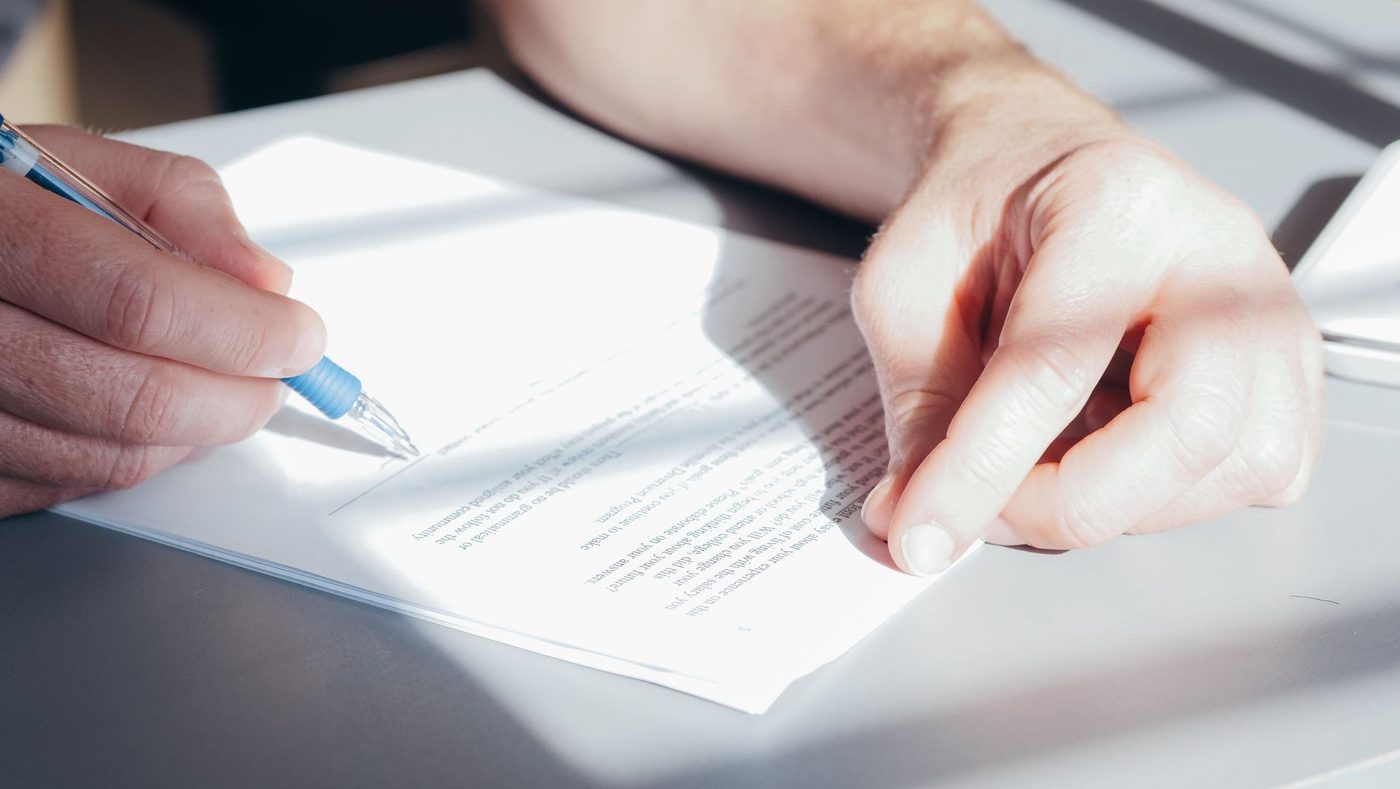Close-up of a hand signing a printed lease or rental agreement document