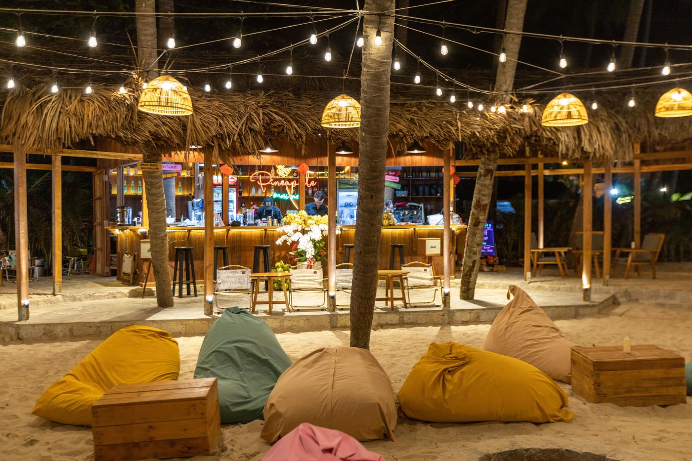 Thatched-roof beach bar glowing with string lights and lanterns at night
