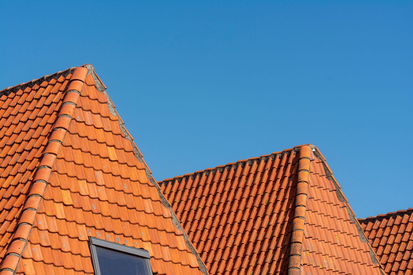 Close-up of red clay tiled rooftops against a clear blue sky