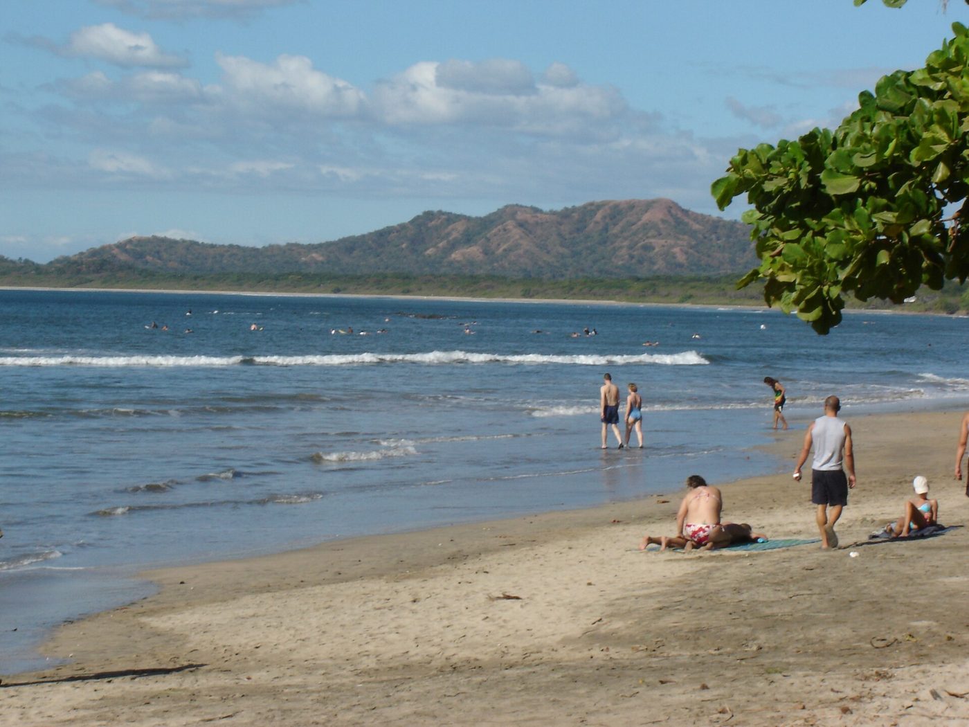 Families swimming and playing in gentle surf at Tamarindo beach in Guanacaste