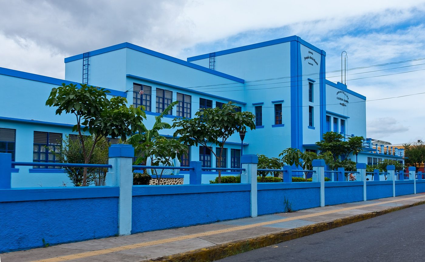 Bright blue Joaquin Garcia Monge public school building behind its painted fence, Costa Rica