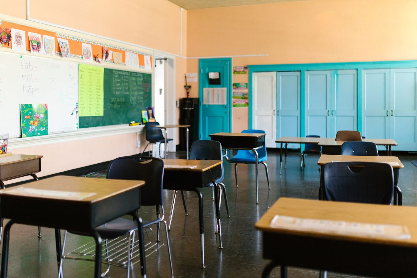 Bright empty classroom with colorful walls, student desks, and a chalkboard, ready for class