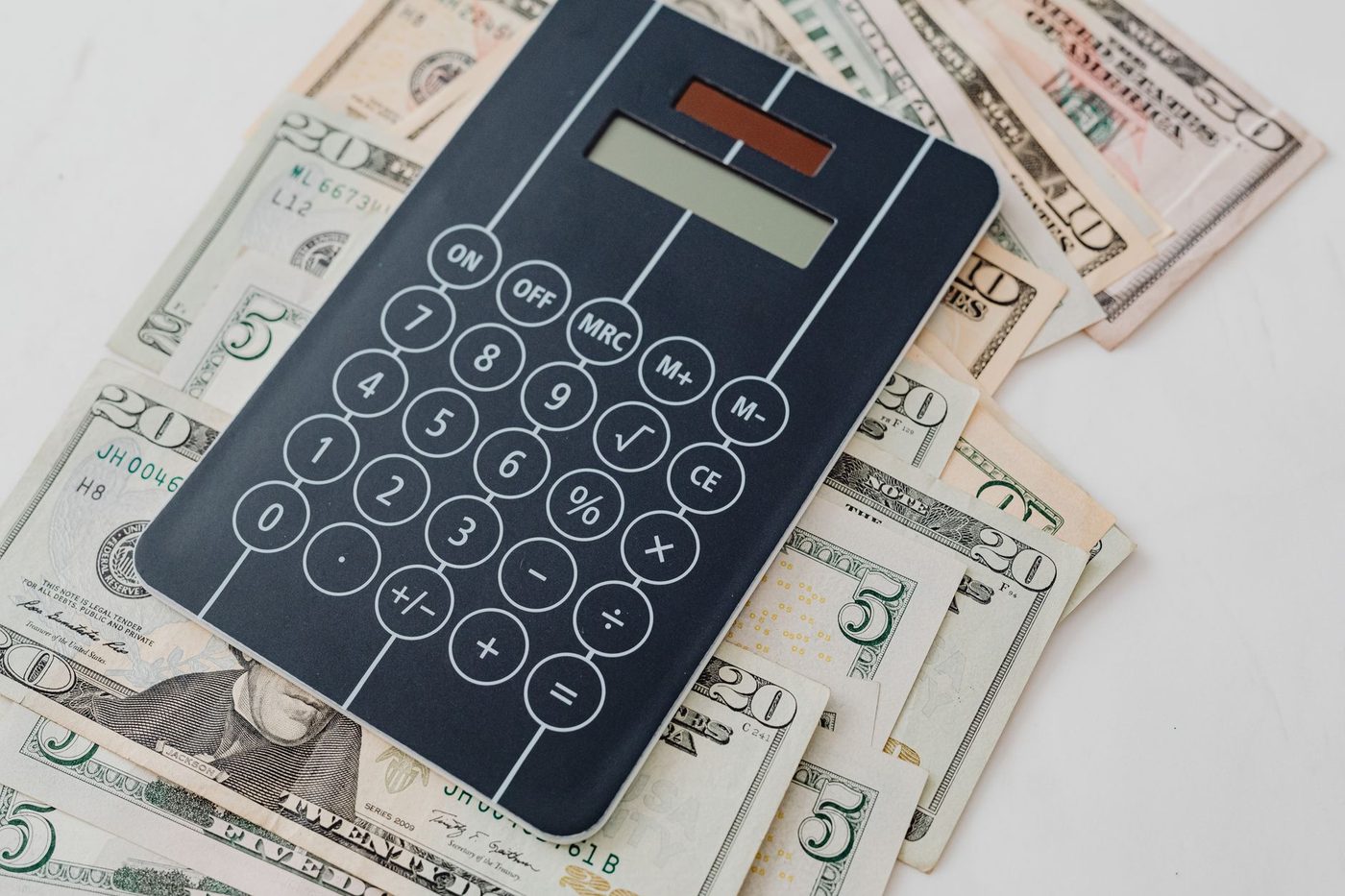 Calculator resting on a spread of dollar bills for figuring sale costs
