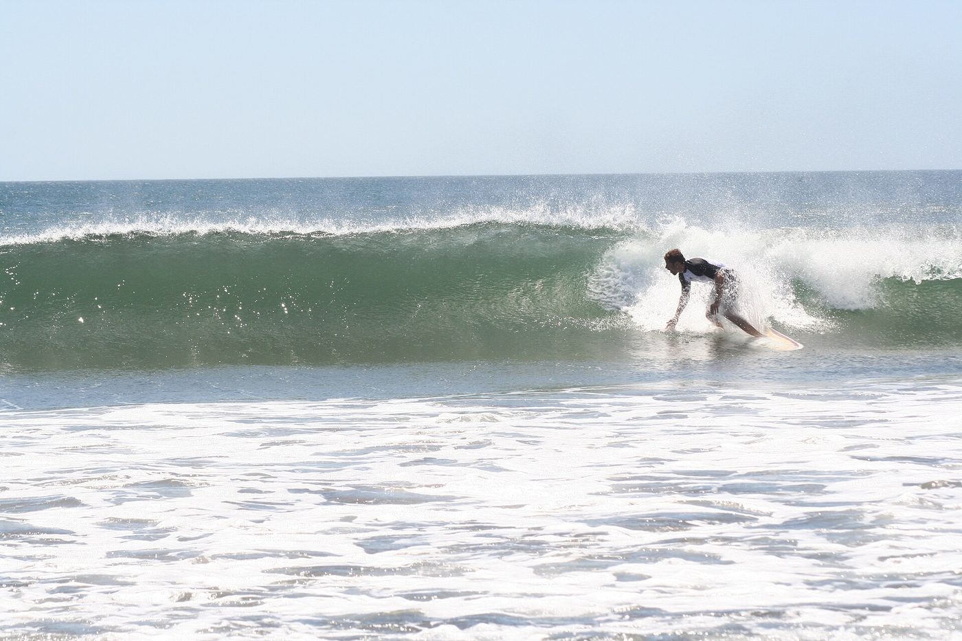 Surfer riding a wave in front of Witch's Rock at Playa Naranjo, Guanacaste