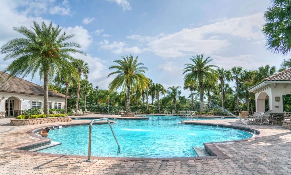 Palm-shaded community pool and clubhouse at a resort-style tropical residential complex