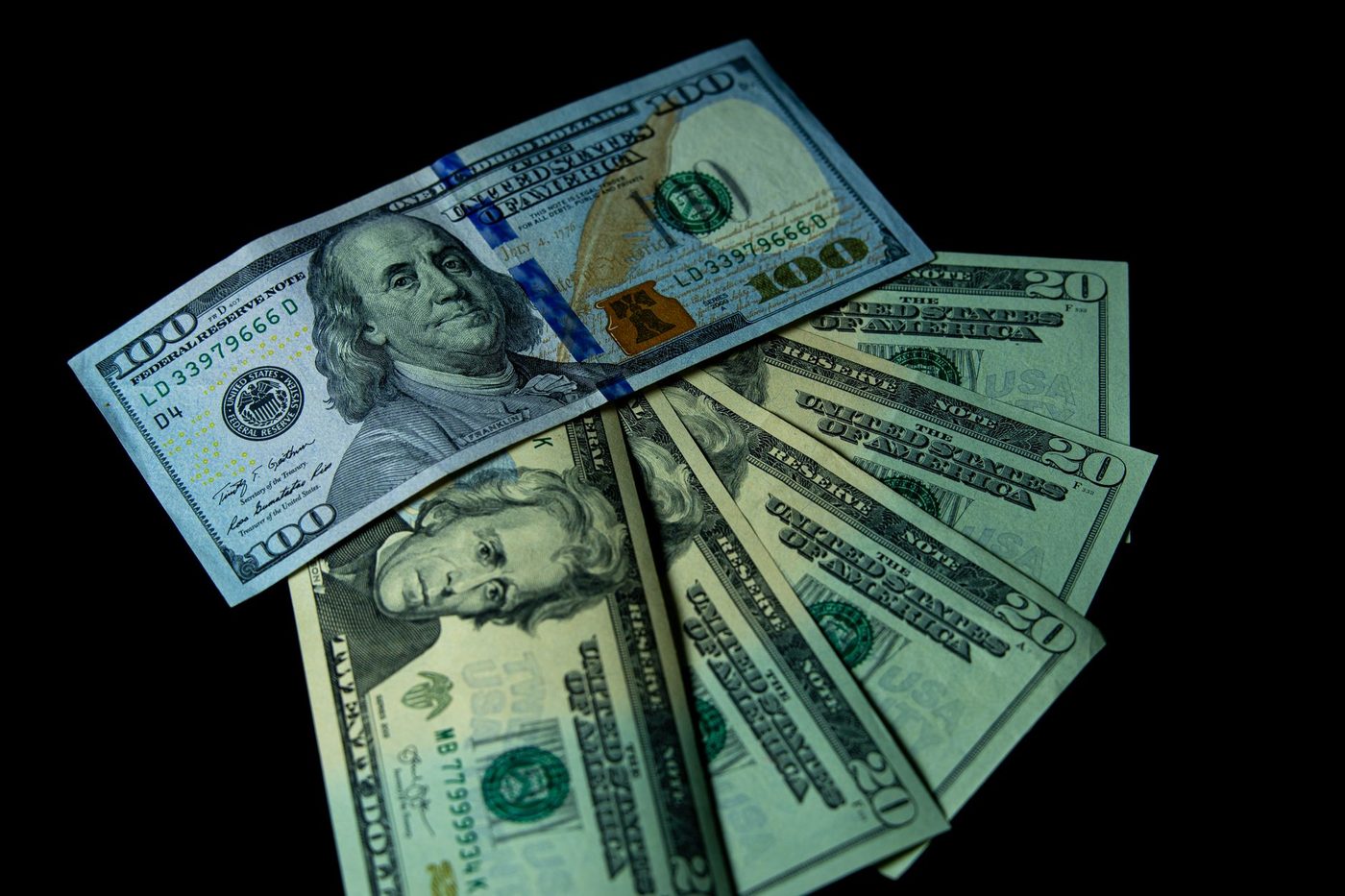 Fanned US dollar bills of different denominations on a dark background