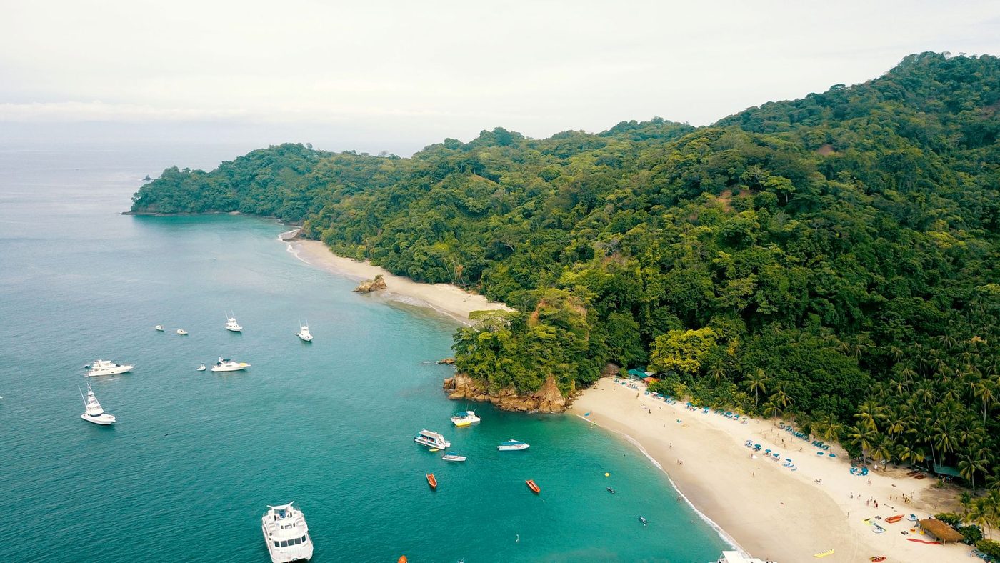 Small fishing boats anchored in a jungle-lined Costa Rican bay from above