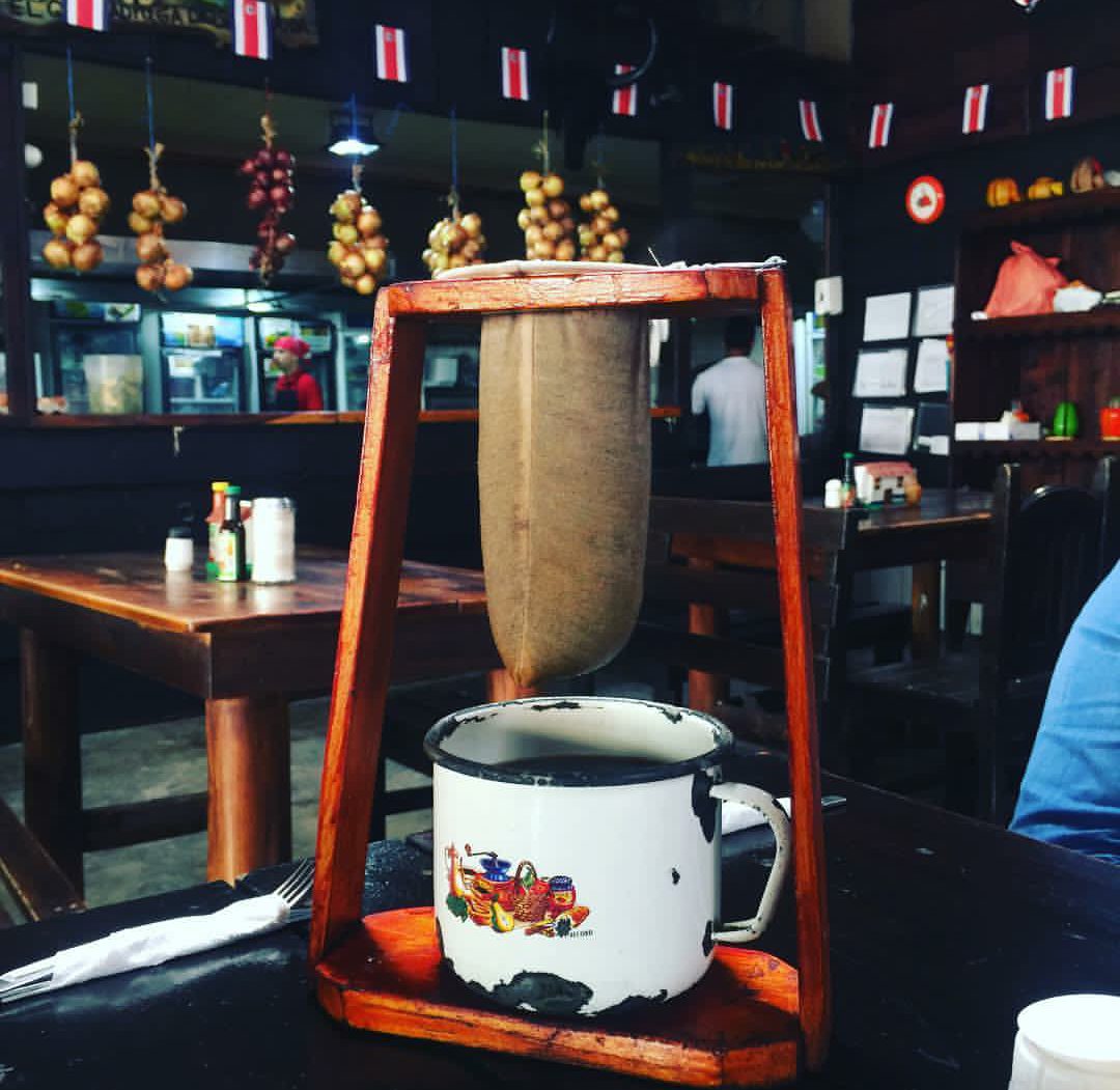 Chorreador dripping fresh coffee into an enamel mug at a Costa Rican cafe