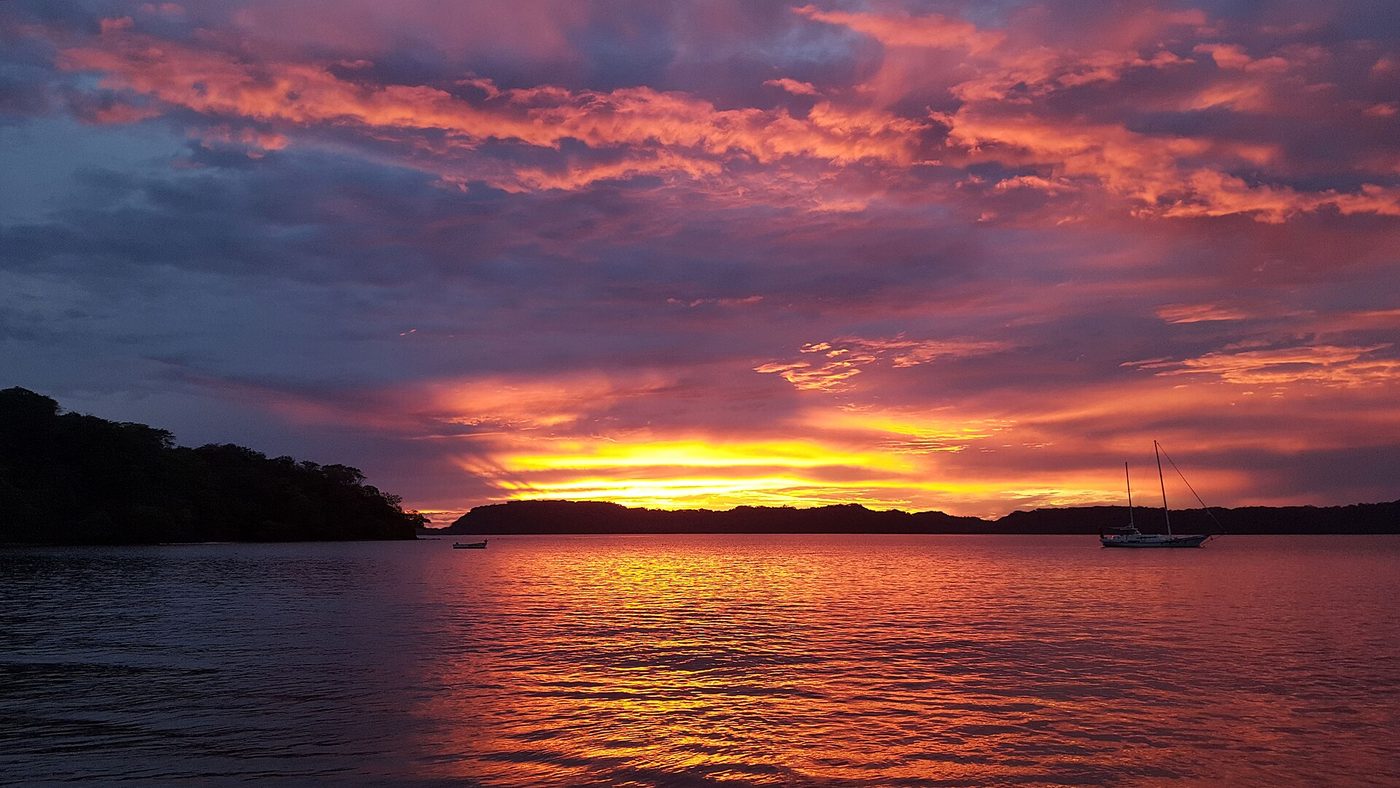 Fiery sunset over Bahia Culebra with a sailboat anchored in calm water