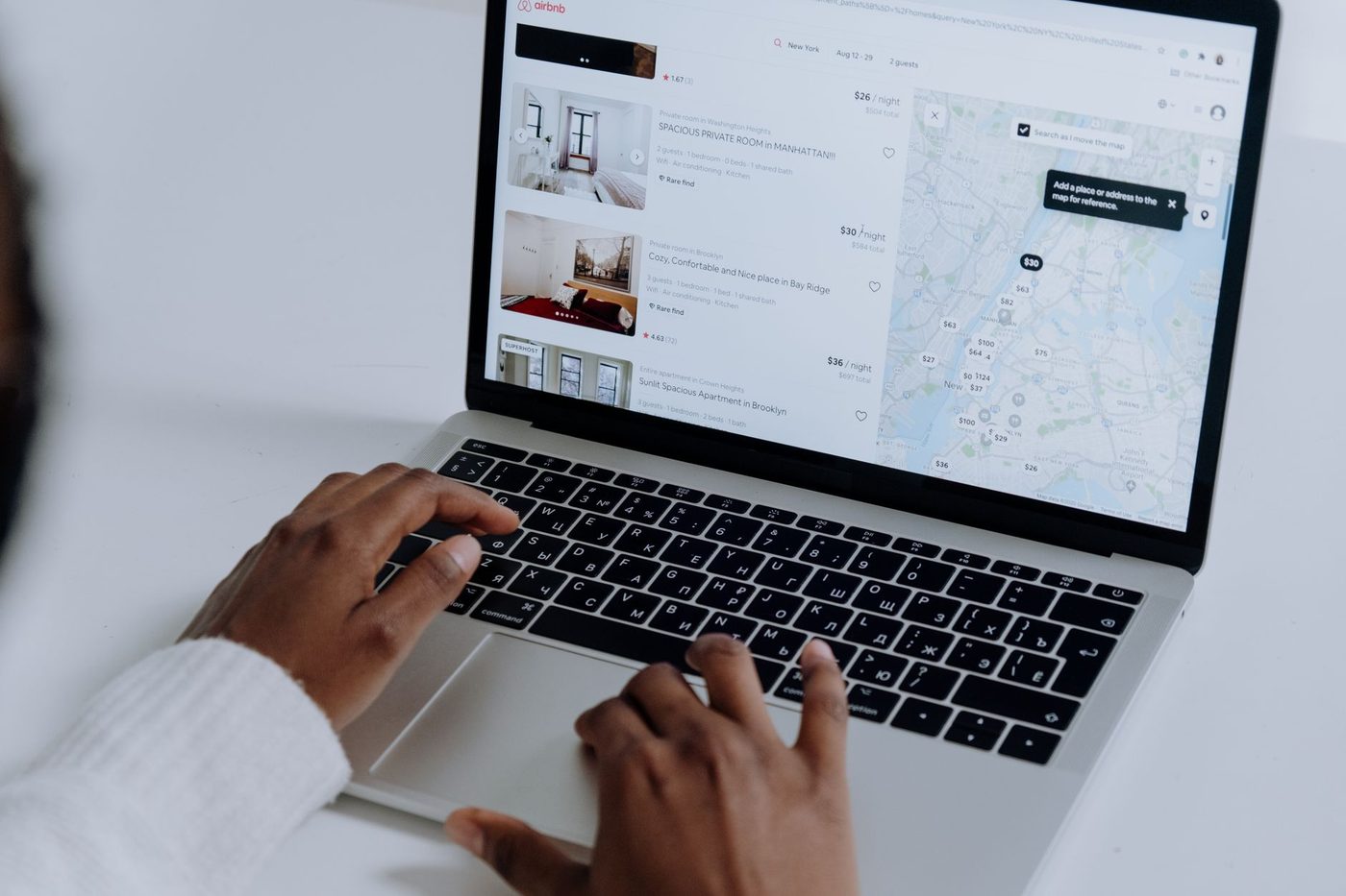 Hands typing on a laptop browsing vacation rental listings with map view
