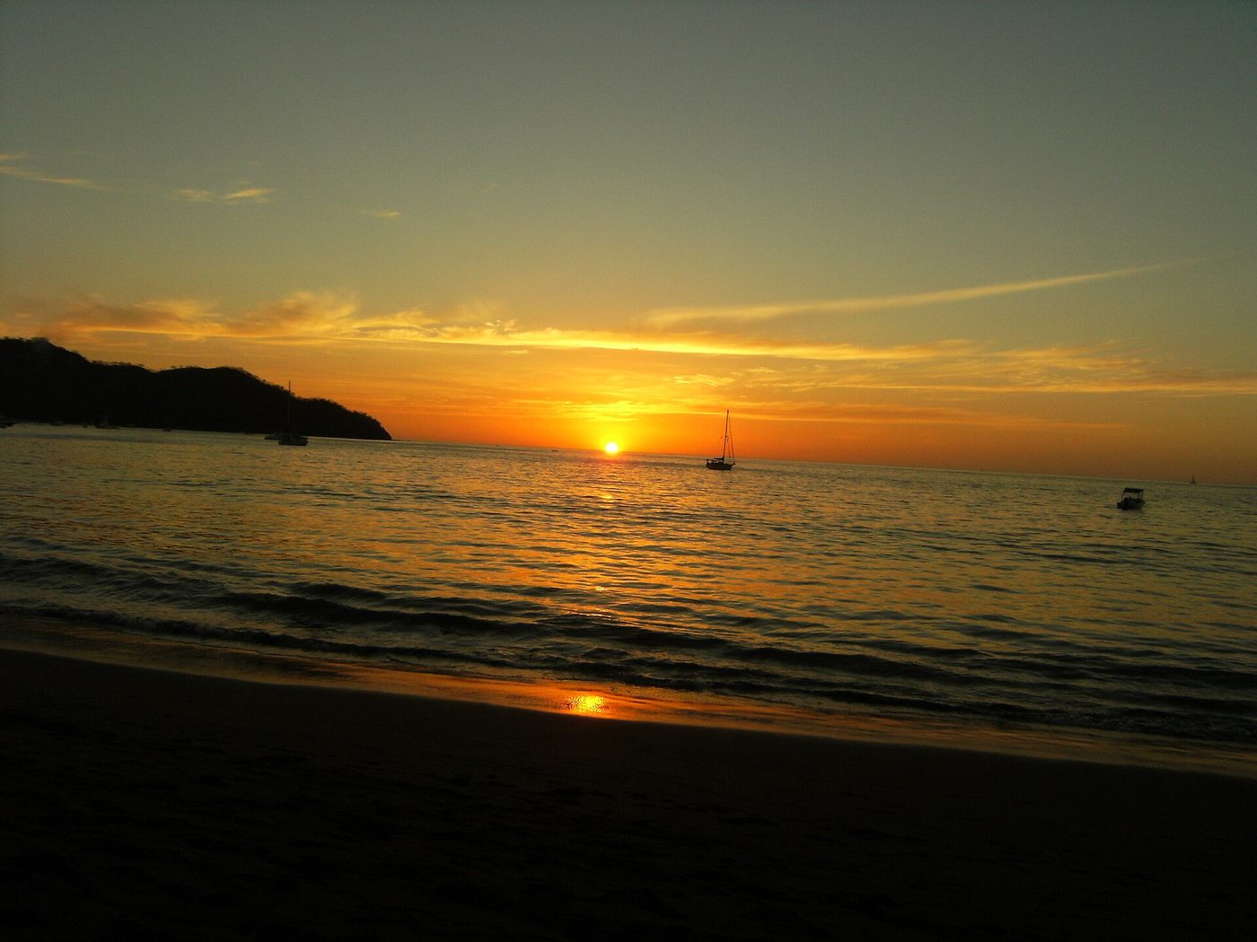 Golden sunset over Coco Bay with sailboats anchored off Playas del Coco beach