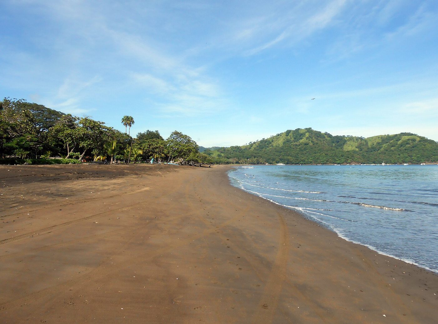 Wide dark sand beach and green headlands on the bay at Playas del Coco, Guanacaste
