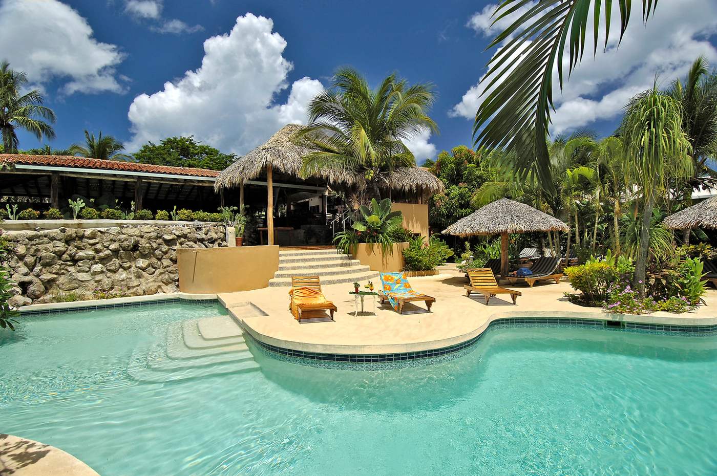 Palm-shaded pool and lounge chairs at a tropical property in Tamarindo, Guanacaste