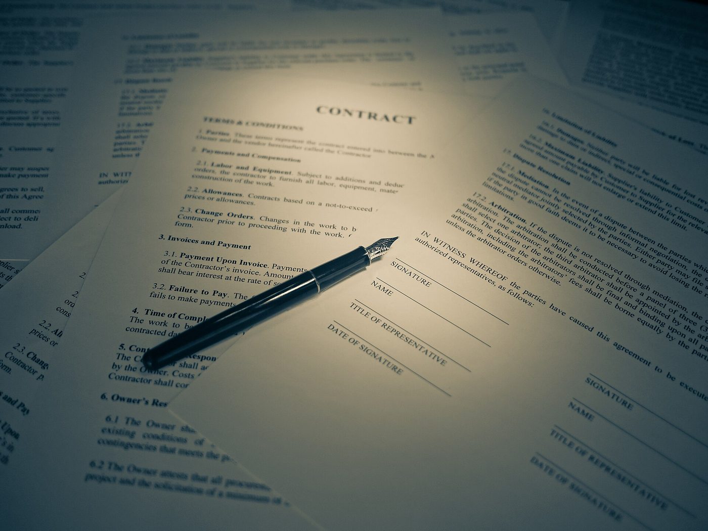 Fountain pen resting on contract pages with signature lines awaiting review